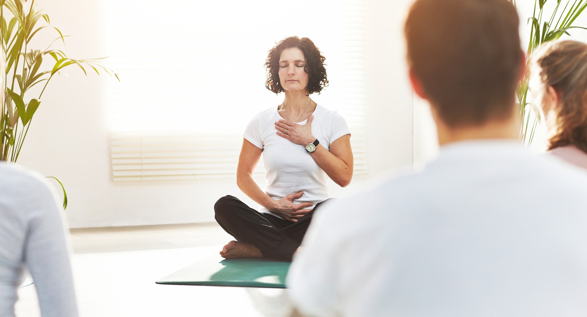 Instructor de yoga entrenando a las personas en una clase de fitness en el estudio. Yogui enseñando técnicas de respiración pranayama con las manos en el pecho y el vientre. Practicar la meditación consciente para la energía zen en la postura del loto